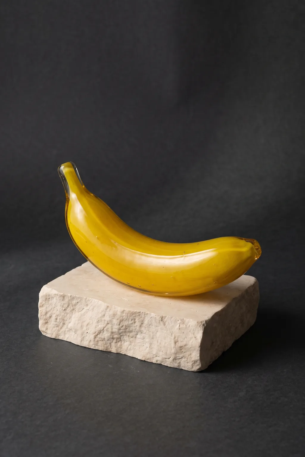 Yellow glass banana resting on a stone block